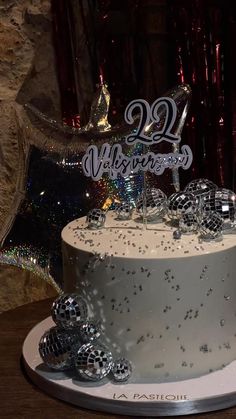 a white cake with silver decorations on it and a large balloon in the shape of a number