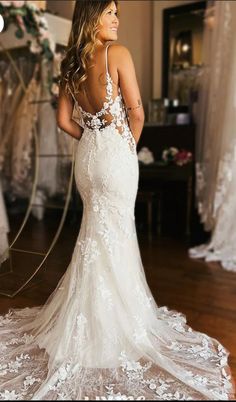 a woman in a wedding dress standing on a wooden floor with her back to the camera