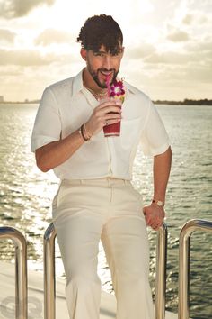 a man holding a drink on top of a boat