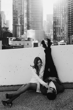 a man and woman laying on the ground next to each other in front of tall buildings