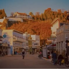 people are riding bikes down the street in front of shops and buildings on a hill