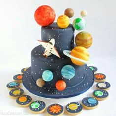 a space themed birthday cake with planets and stars on top, surrounded by cupcakes