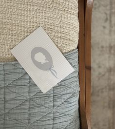 a close up of a bed with a sheet on it and a paper in the corner