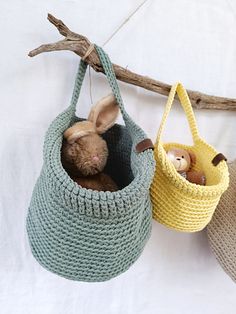 two stuffed animals in baskets hanging from a tree branch