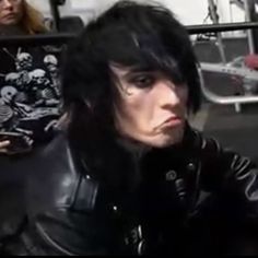 a man with black hair wearing a leather jacket