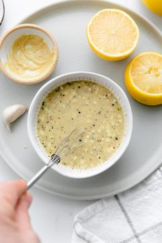 a bowl of soup on a white plate with lemons and an whisk