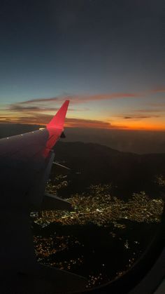 the wing of an airplane as it flies over a city at night with lights on