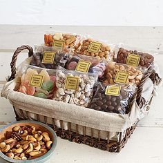 a basket filled with nuts next to a bowl of fruit and crackers on a table