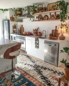 a kitchen filled with lots of counter space and plants on the shelves over the stove