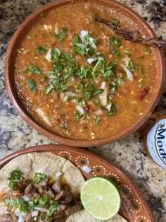 two bowls of soup and tortillas on a table