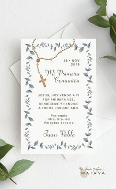 a white card with a cross on it next to some green leaves and greenery