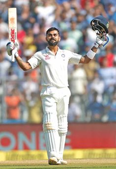 a man holding a cricket bat and ball in his hands while standing on the field