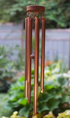 a wind chime hanging from the side of a tree in front of some plants