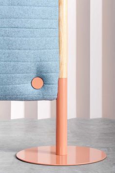 a blue chair with a wooden arm rest on top of a gray table next to a pink and white striped wall