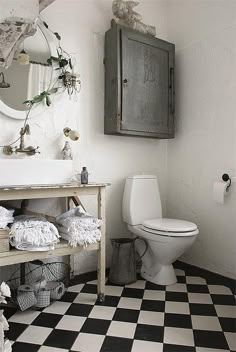 a white toilet sitting next to a sink in a bathroom under a mirror and towel rack