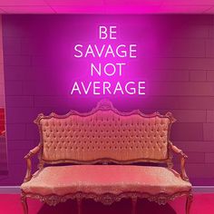 a bench sitting in front of a neon sign that says be savace not average