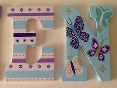 the letter e is made up of wooden letters with butterflies and flowers on them,