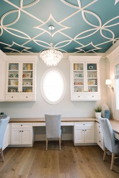 a home office with white cabinets and blue painted ceiling, along with a chandelier hanging from the ceiling