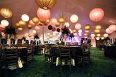 an outdoor event with paper lanterns hanging from the ceiling and tables set up for dinner