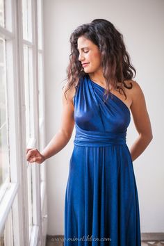 a woman in a blue dress looking out the window