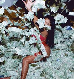 a woman laying on top of a bed covered in lots of money while wearing fishnet stockings