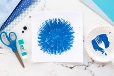 a paper plate with blue paint on it next to scissors and other crafting supplies