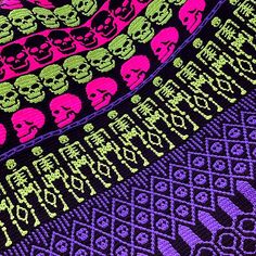 there are many skulls on this knitted blanket that is purple, green and pink