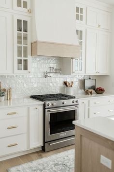 a stove top oven sitting inside of a kitchen next to white cabinets and counter tops