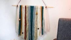 a wall hanging made out of yarn and wooden pegs on a white wall next to a gray chair