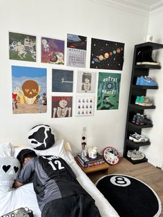 a person laying on top of a bed in a room with pictures hanging on the wall