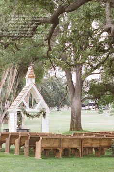 an outdoor wedding venue with benches and a small chapel in the background, surrounded by trees