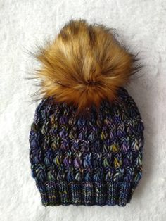 a multicolored knitted hat with a fur pom