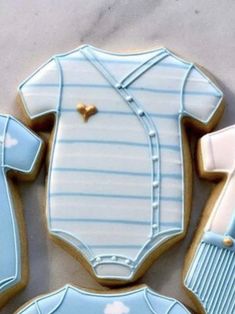 cookies decorated to look like baby clothes and onesuits are laid out on a table