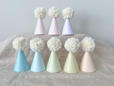 six different colored vases with pom - poms on them