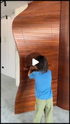 a little boy that is standing in front of a wooden wall with a clock on it