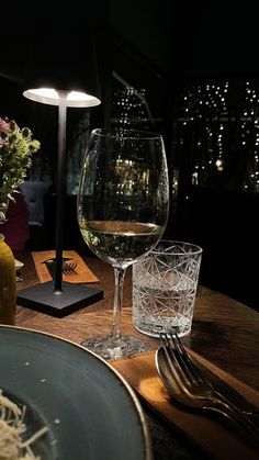 a glass of wine sitting on top of a wooden table next to a vase with flowers