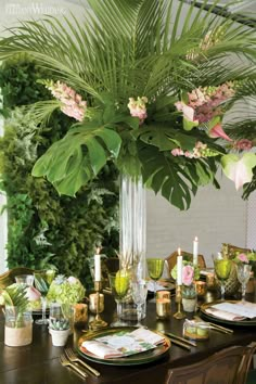 a dining room table set with plates and place settings, flowers in vases on the side