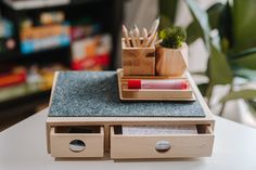 a wooden desk with two drawers holding pens and pencils