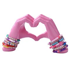 two pink hands making a heart shape with bracelets on each hand and beaded bracelets in the middle