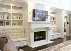 a living room filled with white furniture and a flat screen tv mounted on the wall