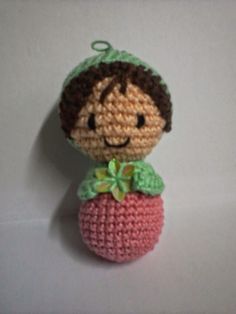 a crocheted doll with a green bow on it's head sitting on a white surface