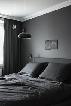 black and white photograph of a bed with two lamps hanging from the ceiling above it