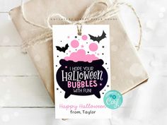 a gift bag with a tag that says happy halloween bubbles on it and bats hanging from the top