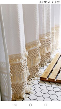 an image of a bathroom setting with white curtains and rugs on the window sill