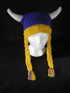 a crocheted viking hat with horns and braids on the front, sitting on a mannequin's head