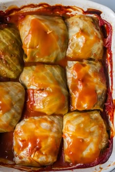 a casserole dish filled with meat and vegetables covered in sauces on top of a white surface