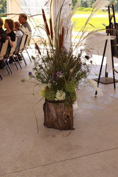 there is a vase with flowers in it on the floor next to people sitting at tables