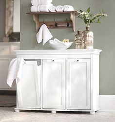 a bathroom with white cabinets and towels on the shelf