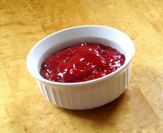 a white bowl filled with red sauce on top of a wooden table