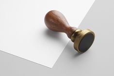 a rubber stamp with a wooden handle on top of a piece of paper next to a pen